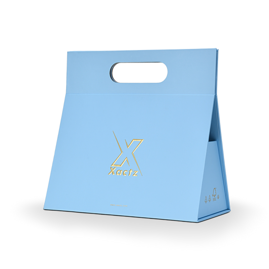 Three quarter angled view of a custom foldable gift box bag with handle in sky blue art paper showing the trapezoidal assembled structure with embossed gold foil logo and FSC certification marks on the side panel