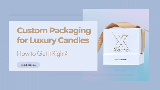 Xactz Blogpost banner custom luxury candle packaging white rigid box with gold foil embossed logo and satin ribbon on soft blue background