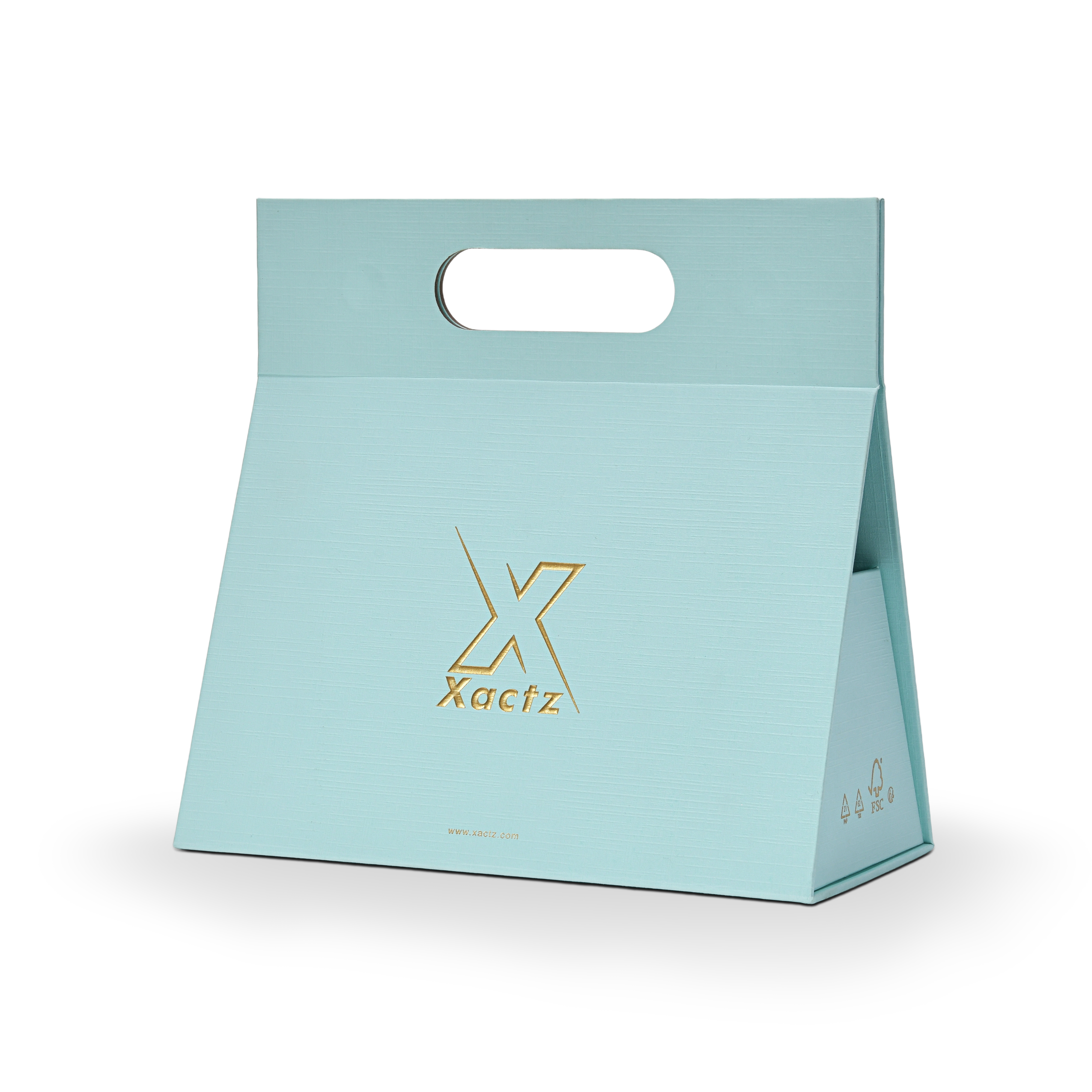 Three quarter angled view of a custom foldable gift box bag with handle in sky blue linen specialty paper showing the tapered trapezoidal body shape with the embossed matte gold foil Xactz logo on the front panel and FSC certification marks in gold on the side panel