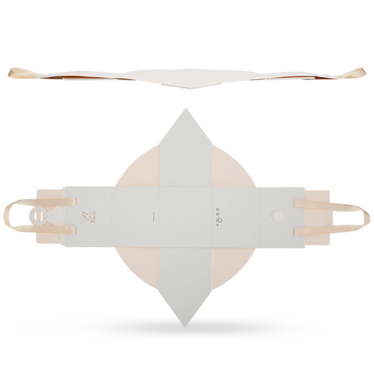 Top down view of an unfolded custom house shaped foldable packaging box showing the cream white textured paper exterior with the gold foil logo and the beige ribbon handles attached to the ends
