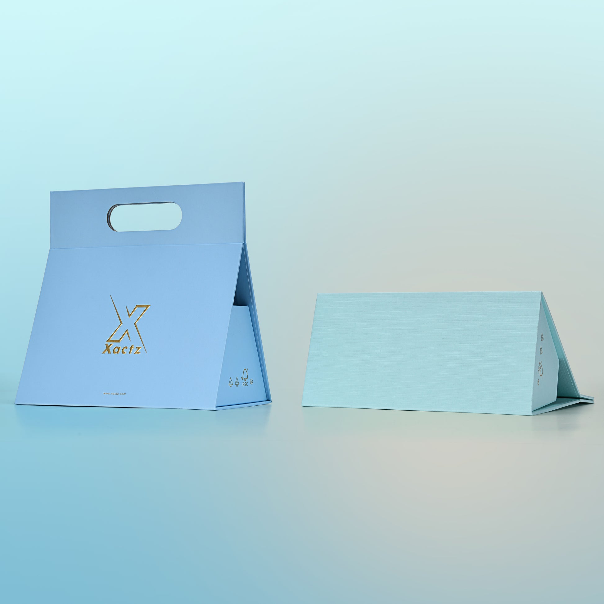Side by side comparison of two custom foldable gift box bags with handle showing the sky blue version fully assembled with gold foil logo on the left and the blank mint green textured specialty paper version in a partially folded flat pack state on the right