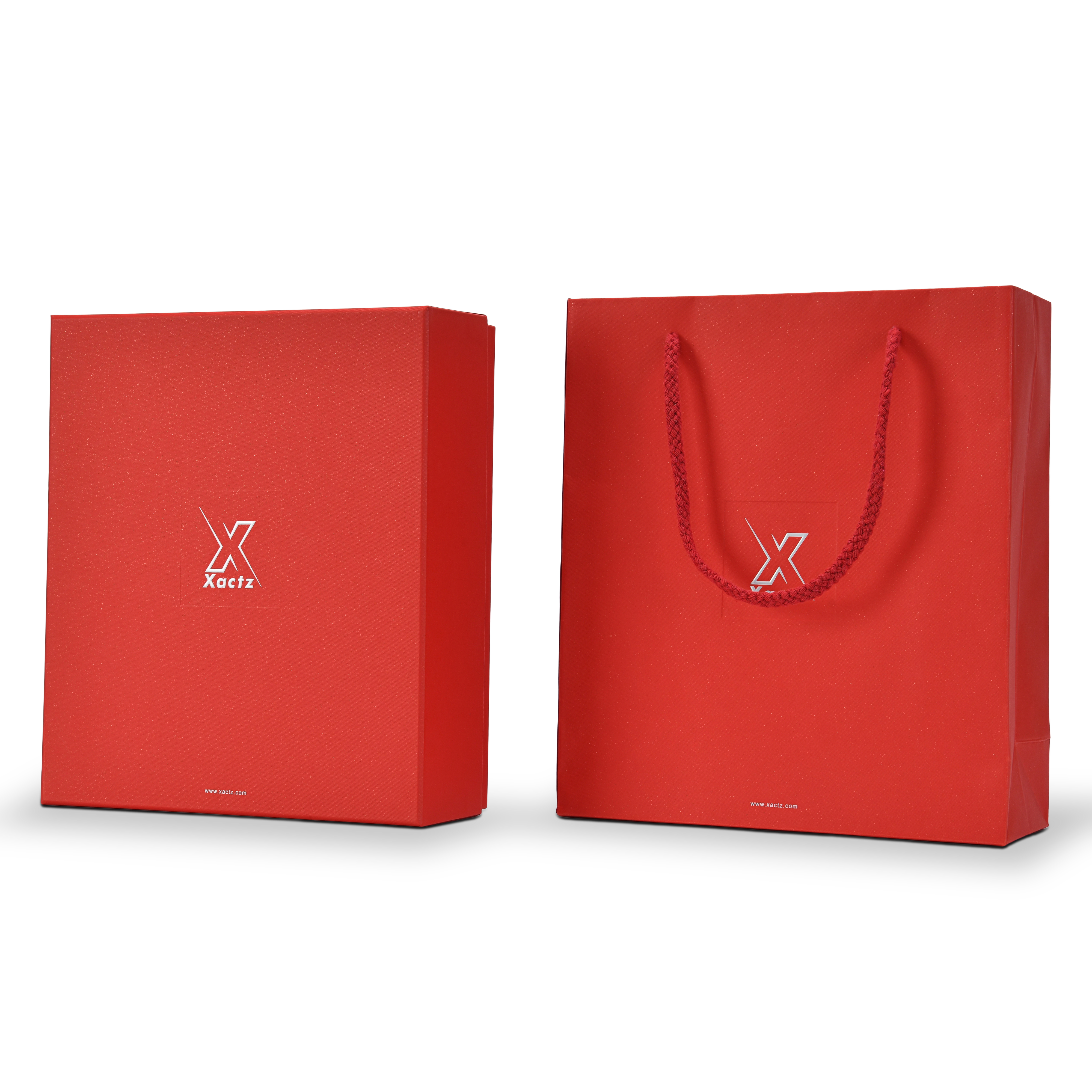 Three quarter angled view of a custom red lid and base gift box for cosmetics shown alongside its matching red specialty paper gift bag both wrapped in deep red star rain specialty paper with embossed bright silver foil Xactz logos and the gift bag displaying a braided red rope handle completing the full premium red and silver cosmetics packaging set