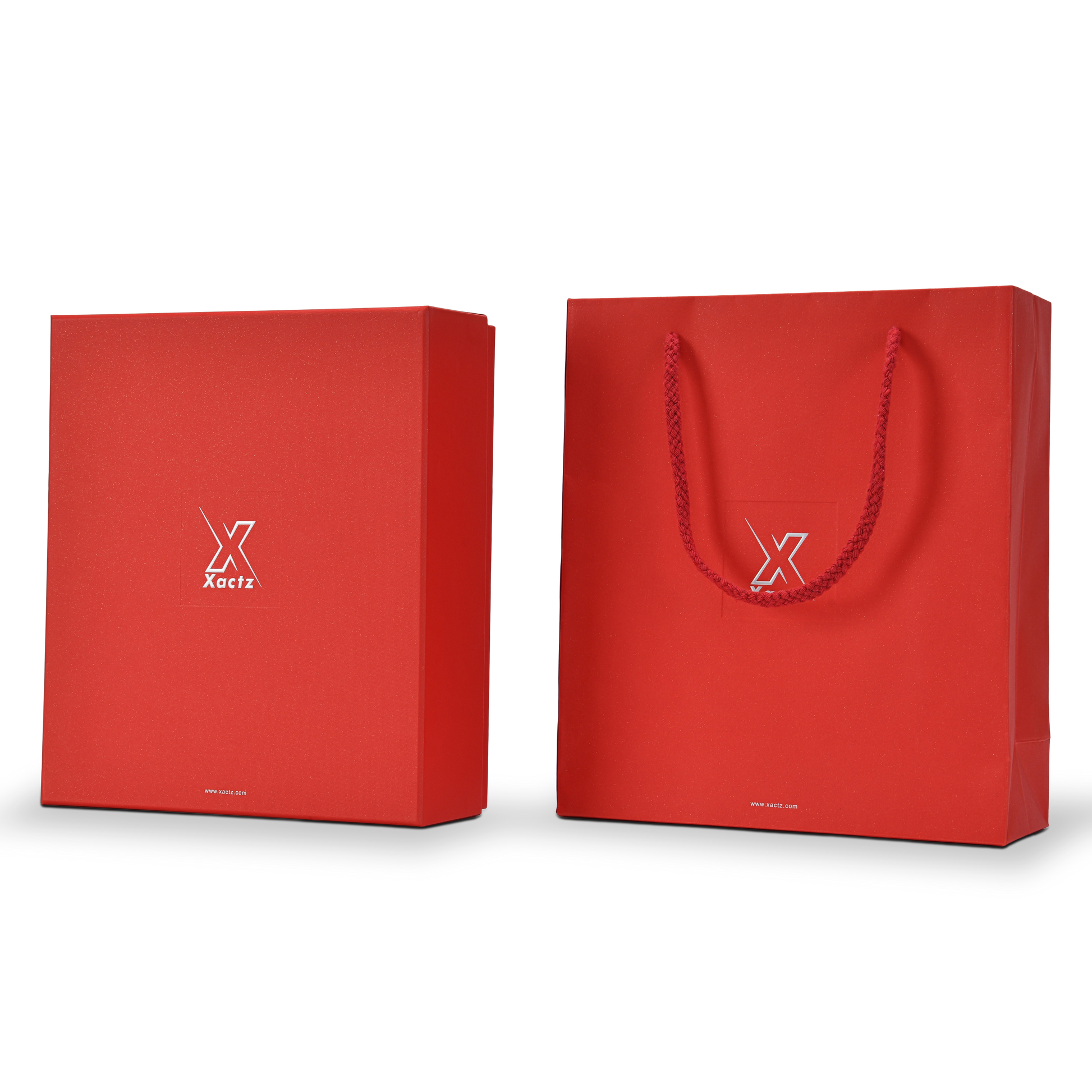 Three quarter angled view of a custom red lid and base gift box for cosmetics shown alongside its matching red specialty paper gift bag both wrapped in deep red star rain specialty paper with embossed bright silver foil Xactz logos and the gift bag displaying a braided red rope handle completing the full premium red and silver cosmetics packaging set