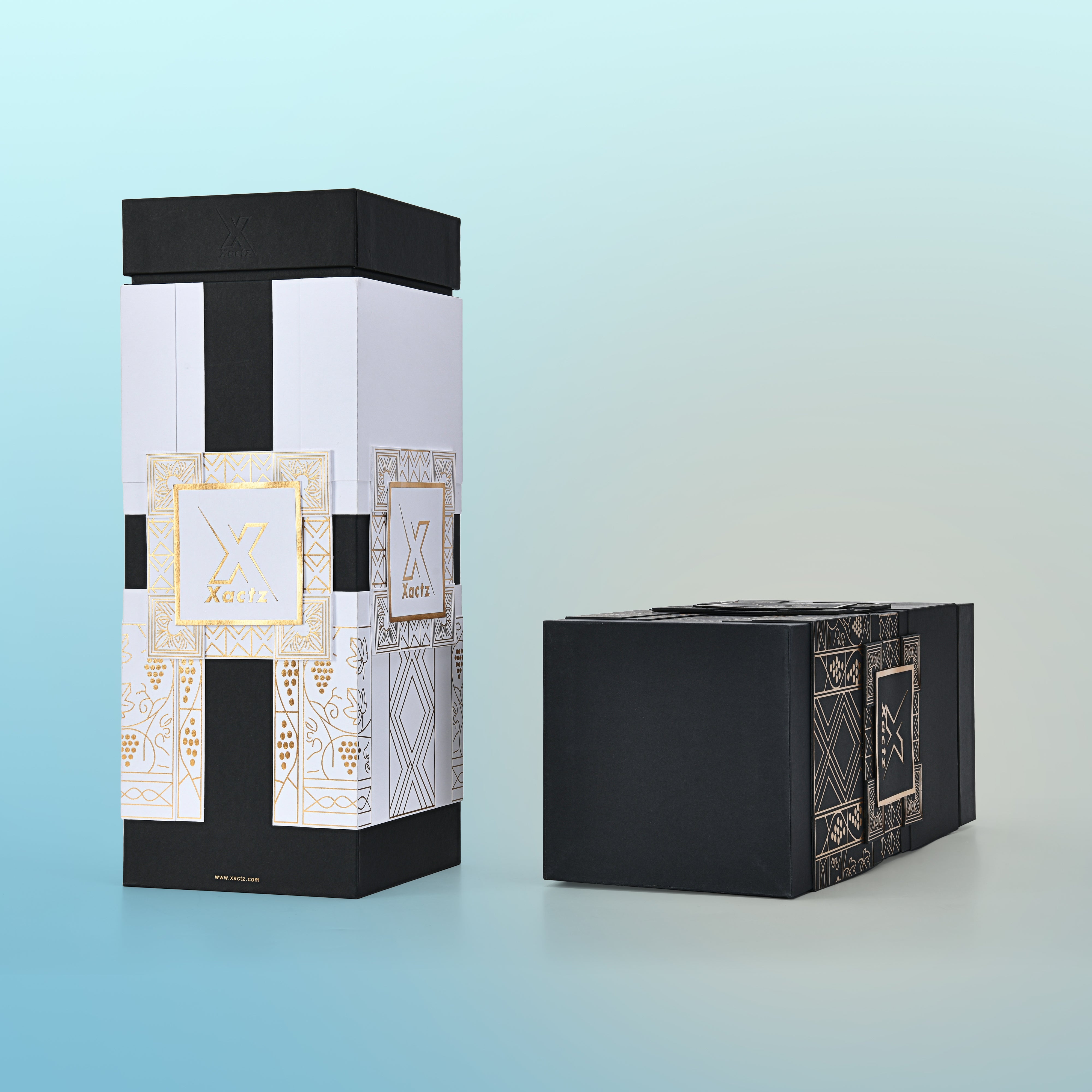 Two custom black rigid wine gift boxes displayed side by side with lids separated showing the white body gold foil version standing upright and the all black gold foil version lying on its side both revealing the full collared base construction and the detailed gold foil grape vine and geometric illustration panels