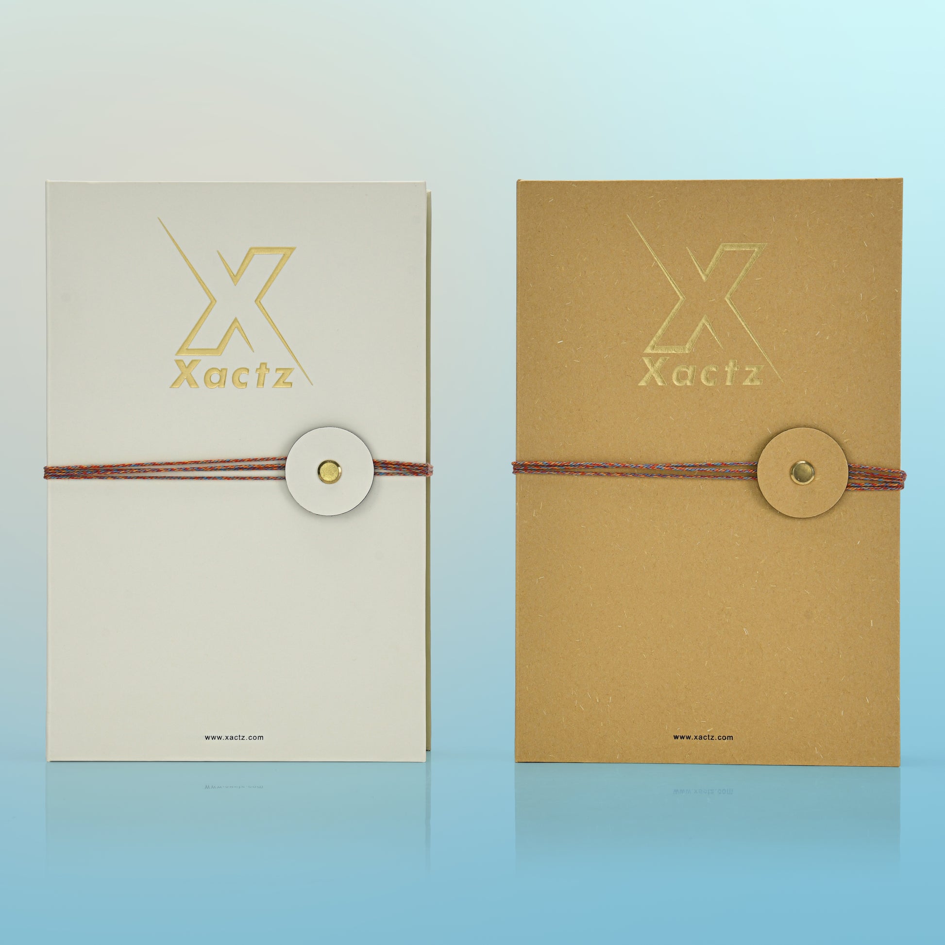 Luxury cream and kraft book style perfume gift box front view comparison showing embossed gold foil Xactz logo and multicolour rope closure with gold metal rivet on both soft-touch laminated cream and natural kraft variants