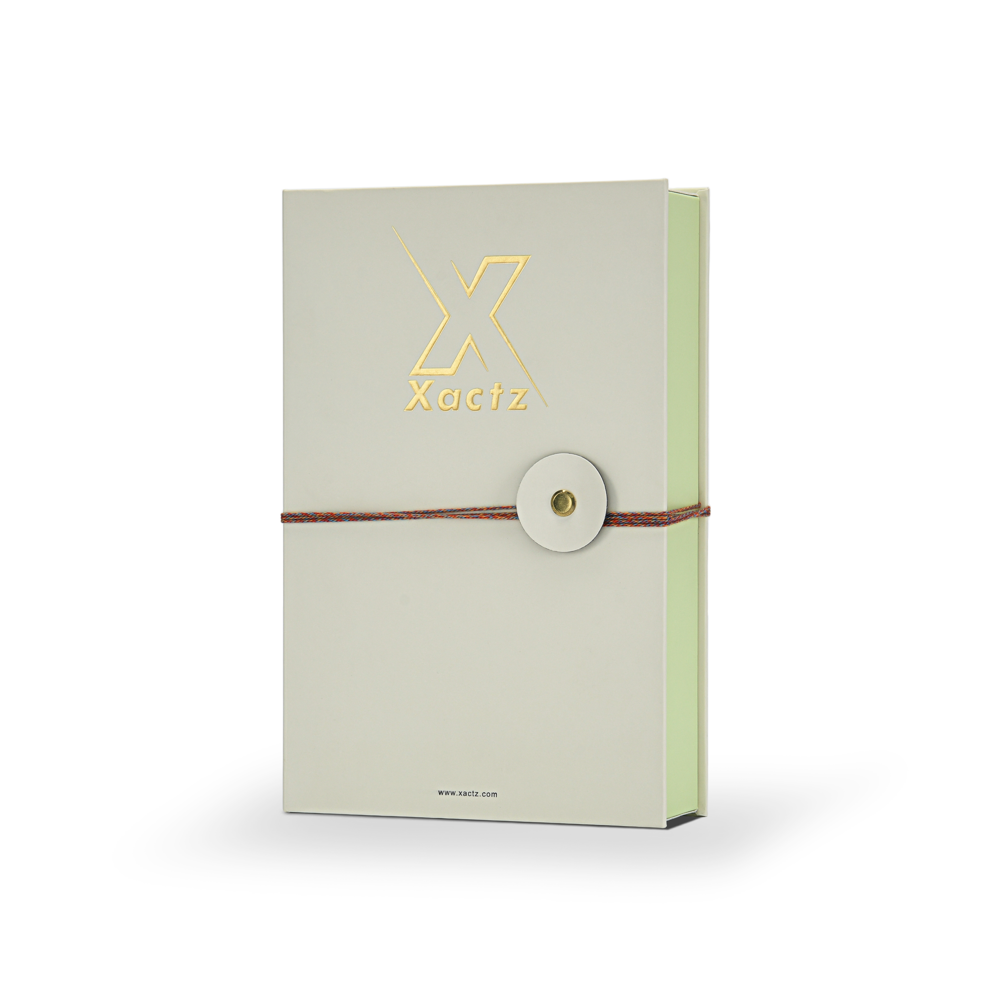 Luxury cream book style perfume gift box three quarter angle view showing embossed gold foil Xactz logo soft-touch matte lamination pale green interior spine and multicolour rope closure with gold metal rivet