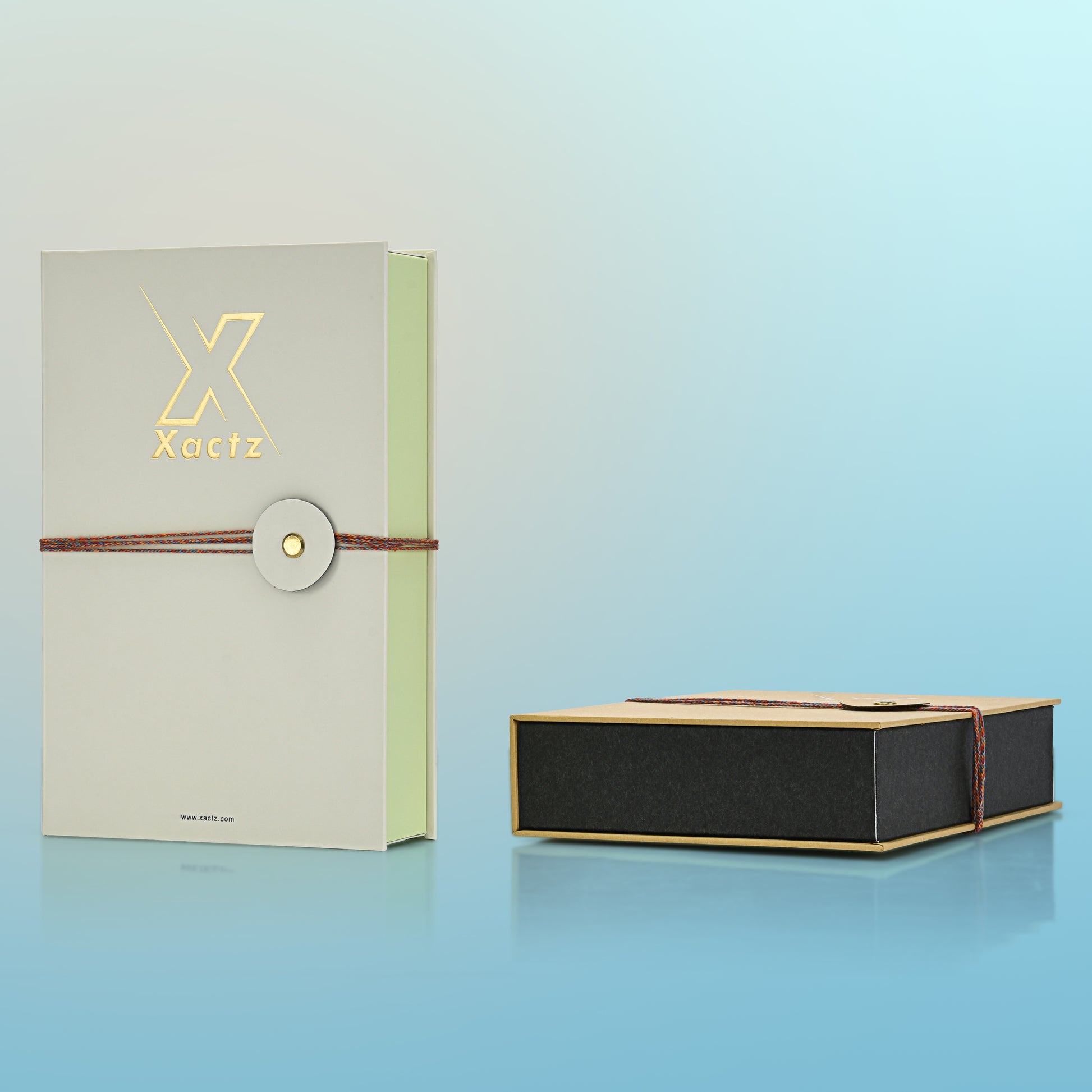 Luxury cream book style perfume gift box three quarter angle view alongside open kraft variant showing black interior base construction and multicolour rope closure detail on both rigid book style perfume packaging variants